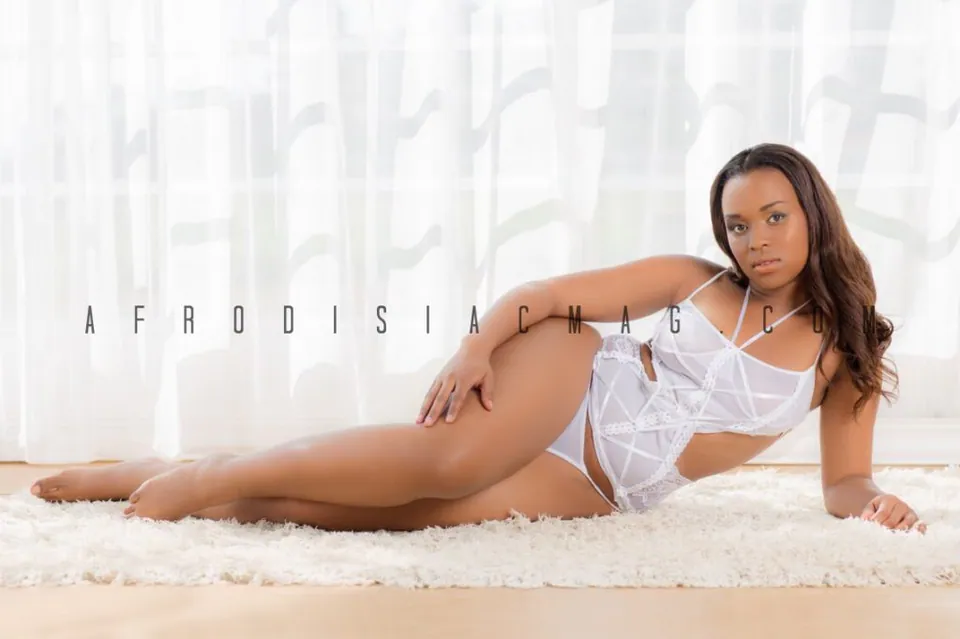 Model in white lingerie reclining on a white rug by a sunlit window